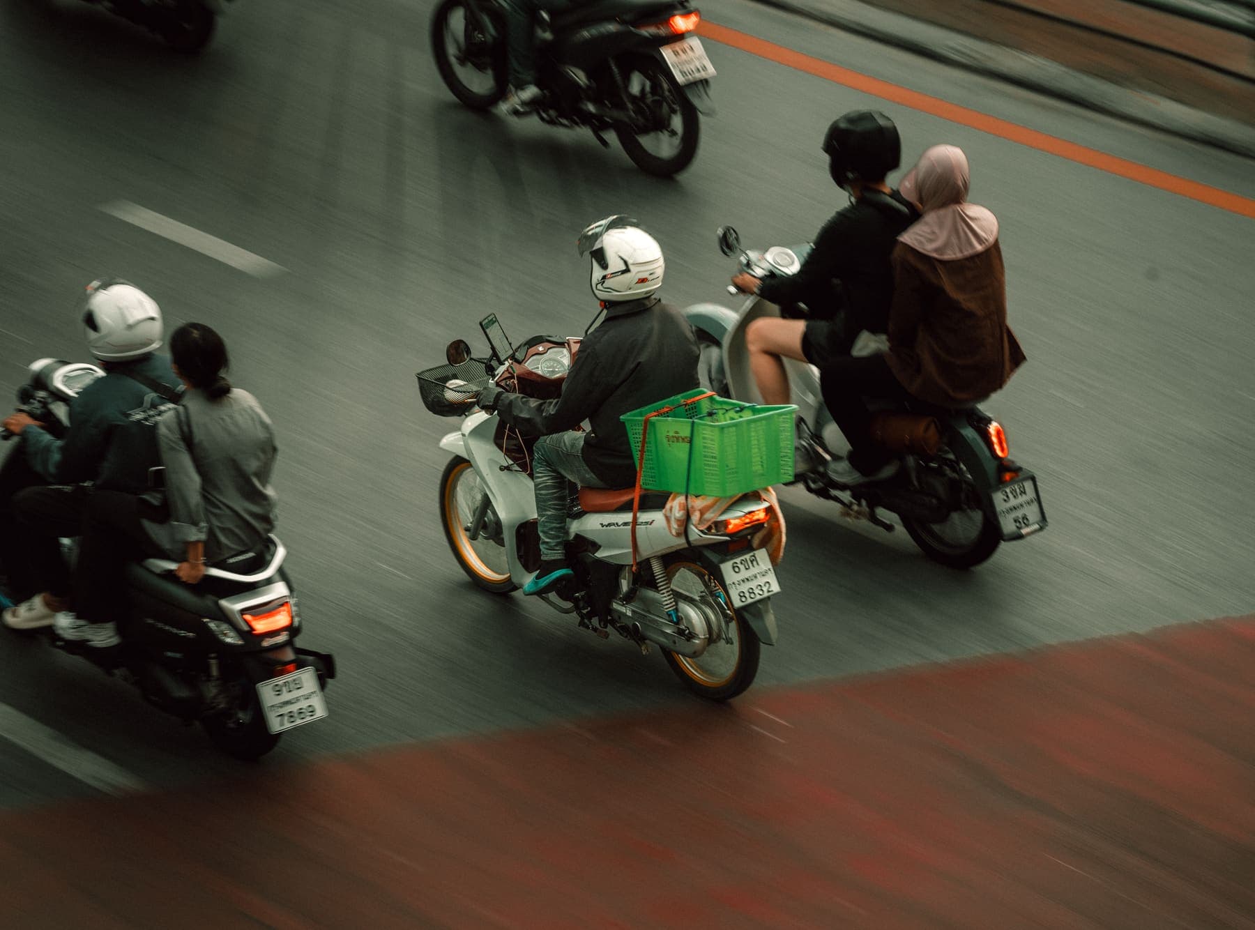 Mehrere Motorräder fahren gemeinsam eine Straße entlang, mitgezogen fotografiert, sodass der Hintergrund verschwimmt