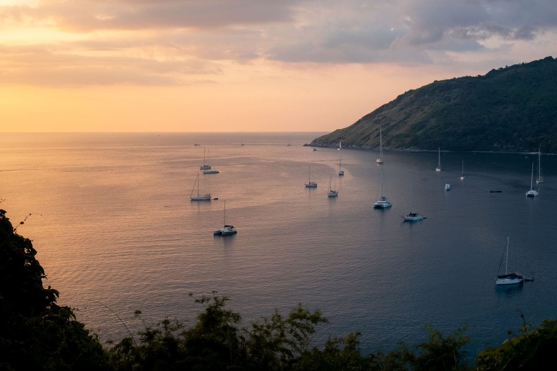 Segelboote und Yachten vor Anker in einer Bucht auf Phuket gegen Sonnenuntergang
