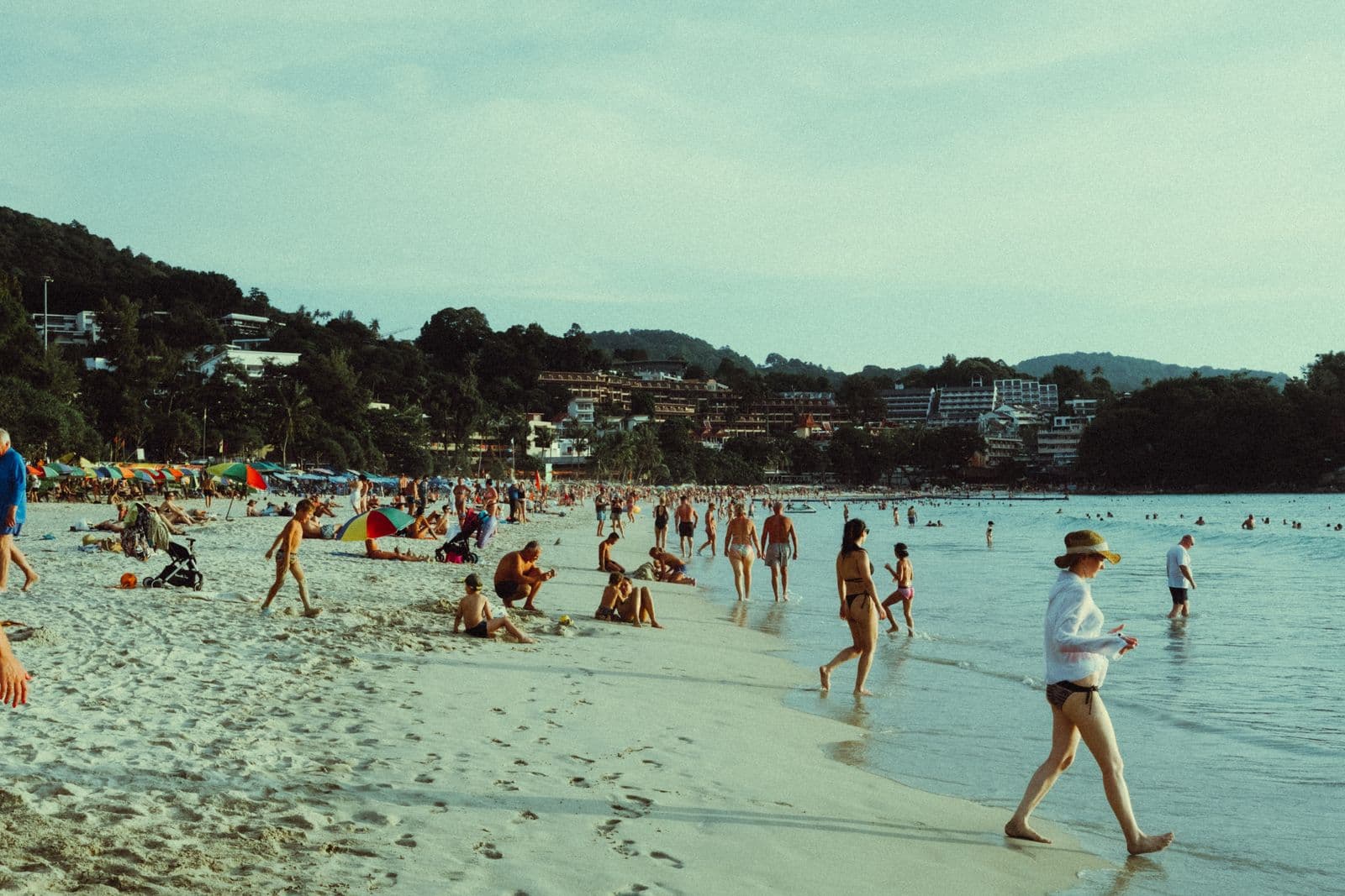 Menschen im flachen Wasser an einem belebten Strand in Patong